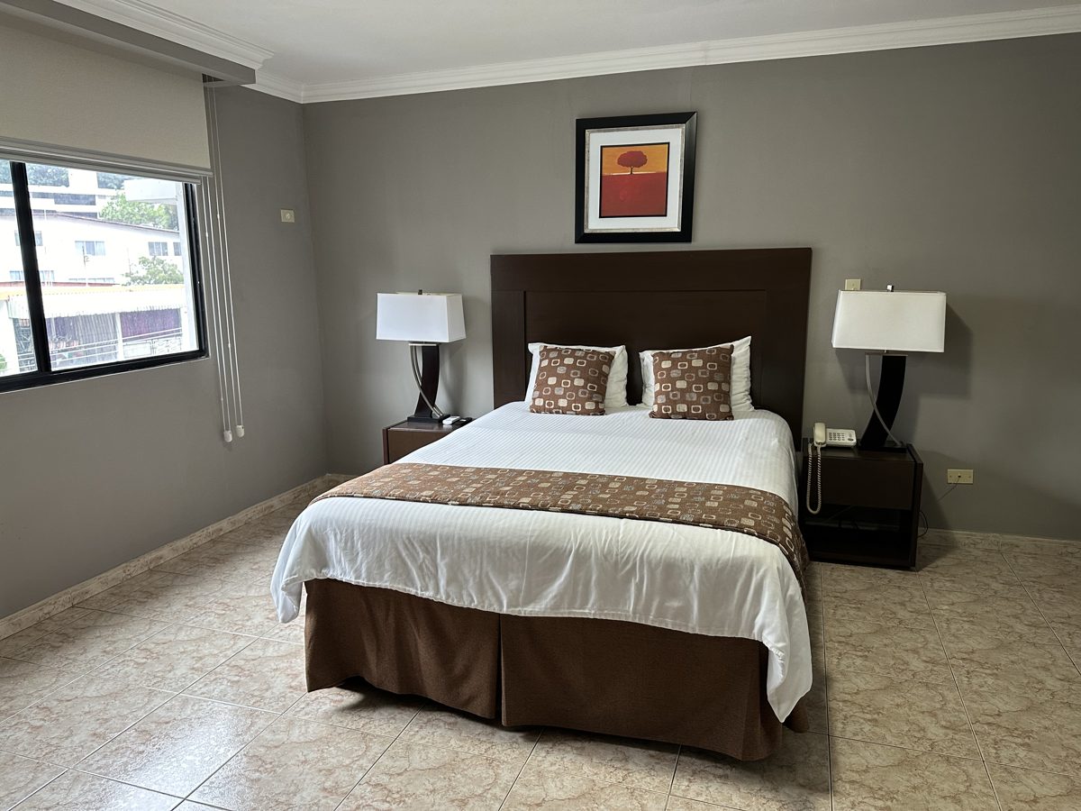 Suite Ejecutiva — dormitorio privado con cama Queen y mesitas de noche